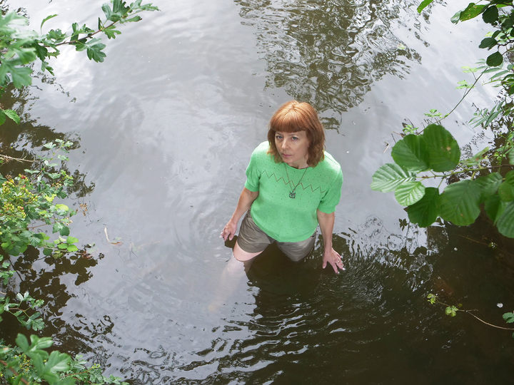 Artist Feral Practice looking up at camera while standing in the River Tone
